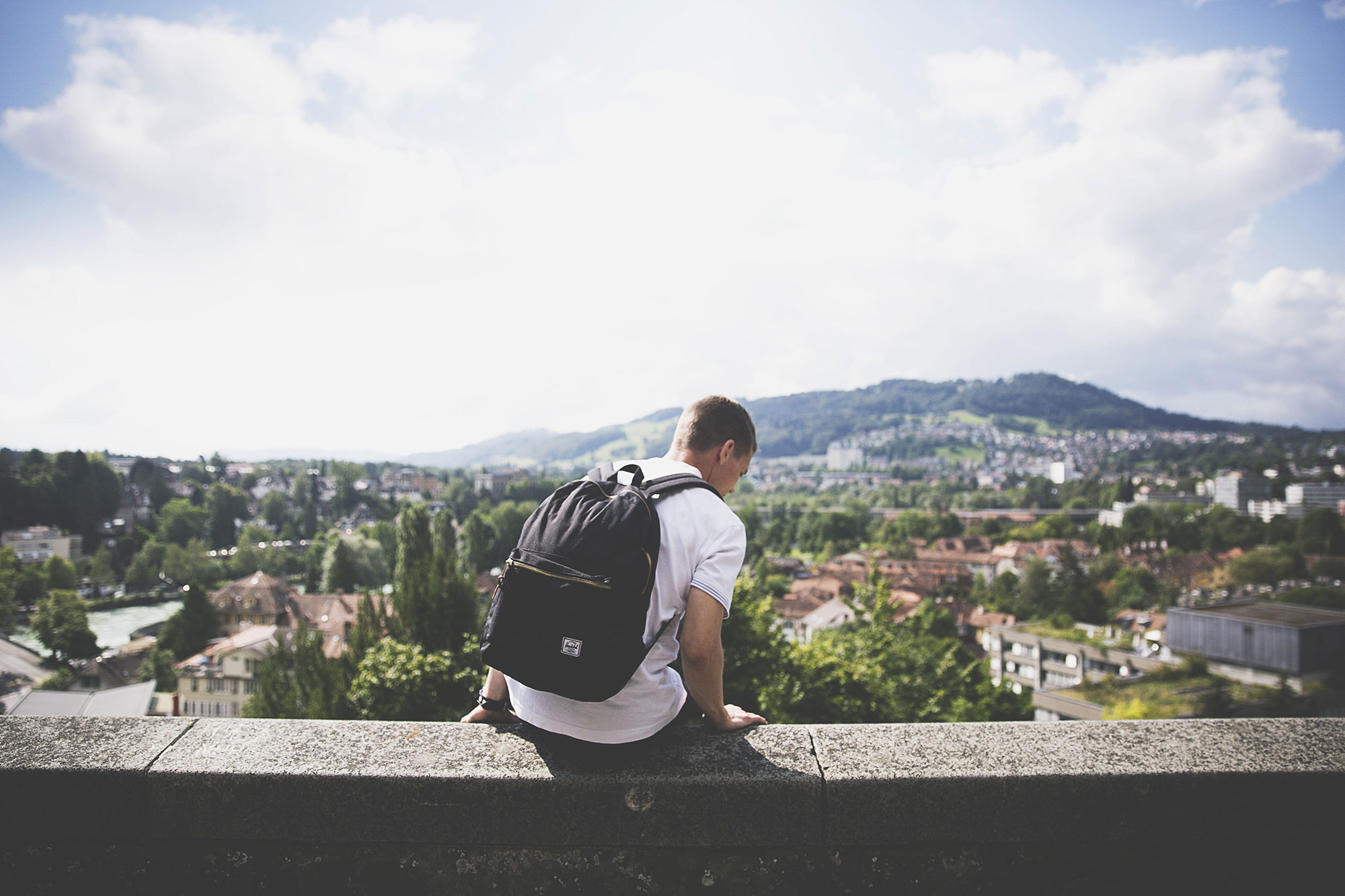 backpacker-sitting-on-wall-and-looking-down-on-town